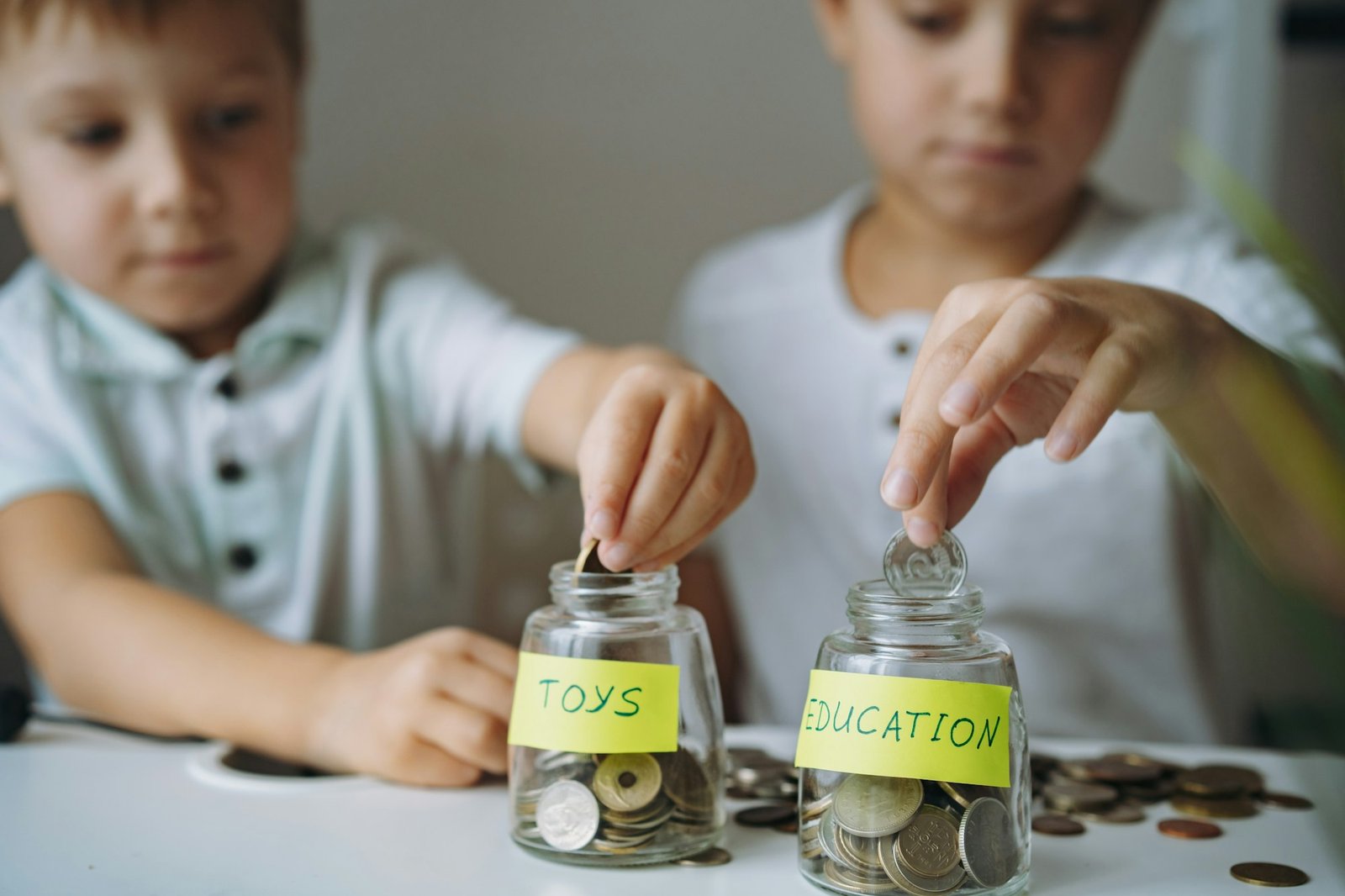 two boys put cois into glass jars. savings for toys or education